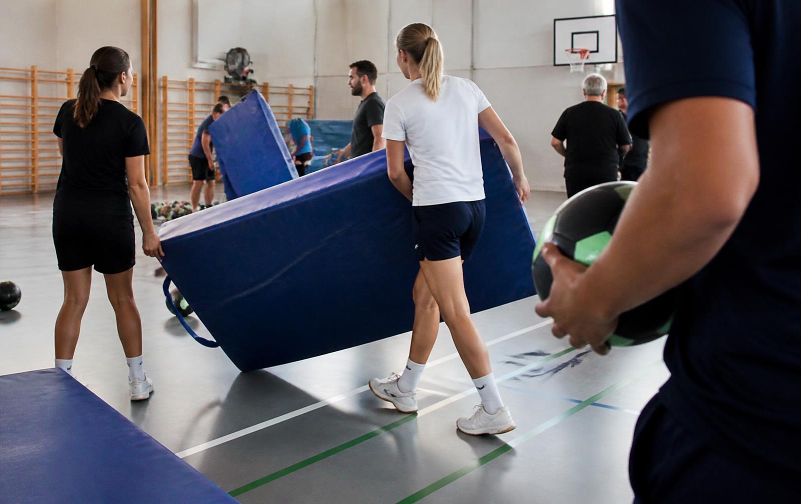 Människor hjälps åt att plocka undan utrustning i en sporthall